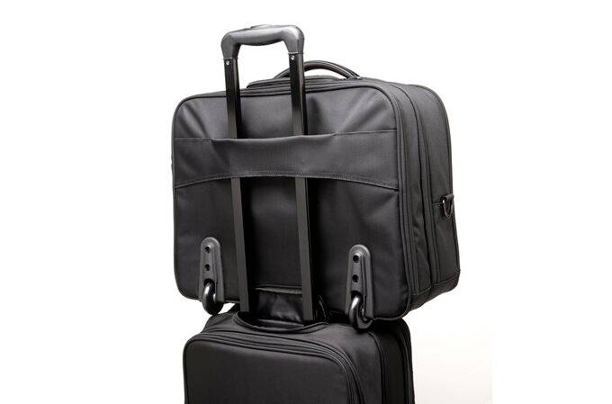Czarna torba podróżna na kółkach stoi pionowo i jest połączona z teleskopową rączką poprzez uchwyt.