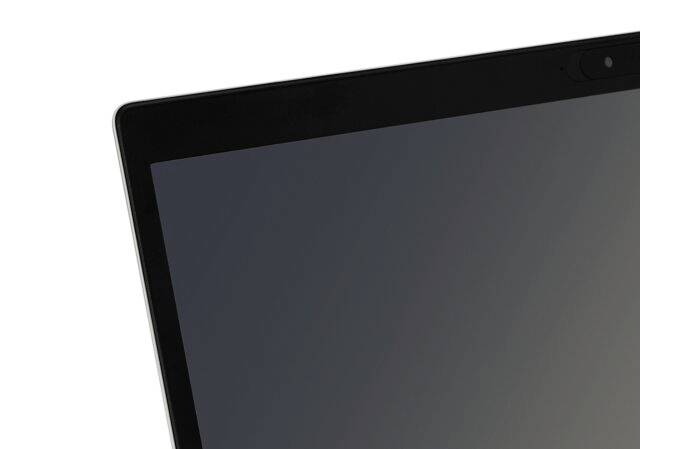 Fragment ekranu laptopa w górnym rogu, sfotografowany pod skosem, z widoczną małą kamerką przy krawędzi.