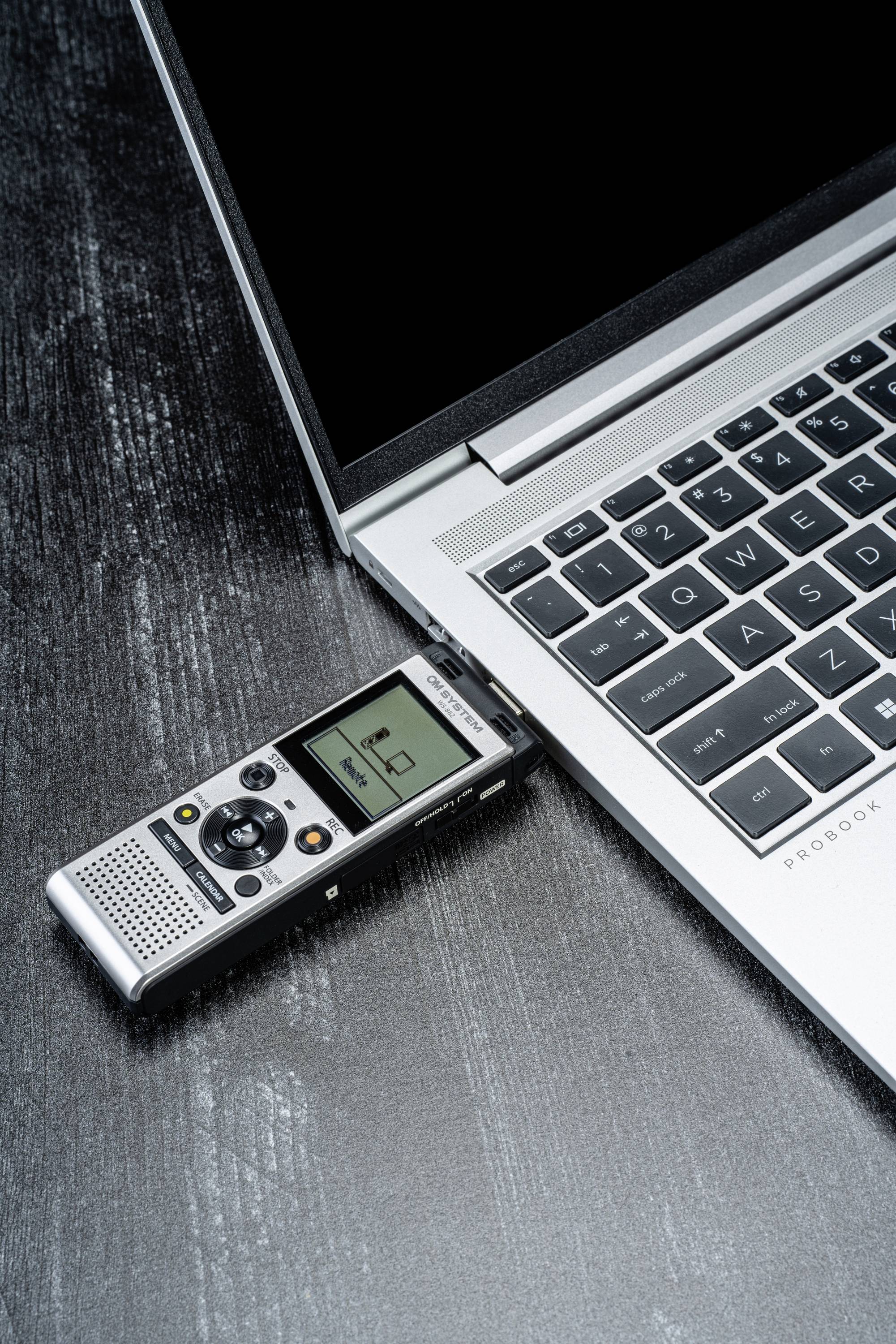 Cyfrowy rejestrator dźwięku jest podłączony do laptopa i wyświetla informacje na małym ekranie.