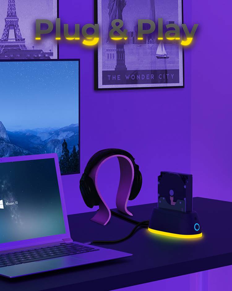 Biurko z laptopem, słuchawkami i stacją dokujące do dysków twardych. W tle widoczne są znane zabytki. Tekst u góry wyświetla napis "Plug & Play".