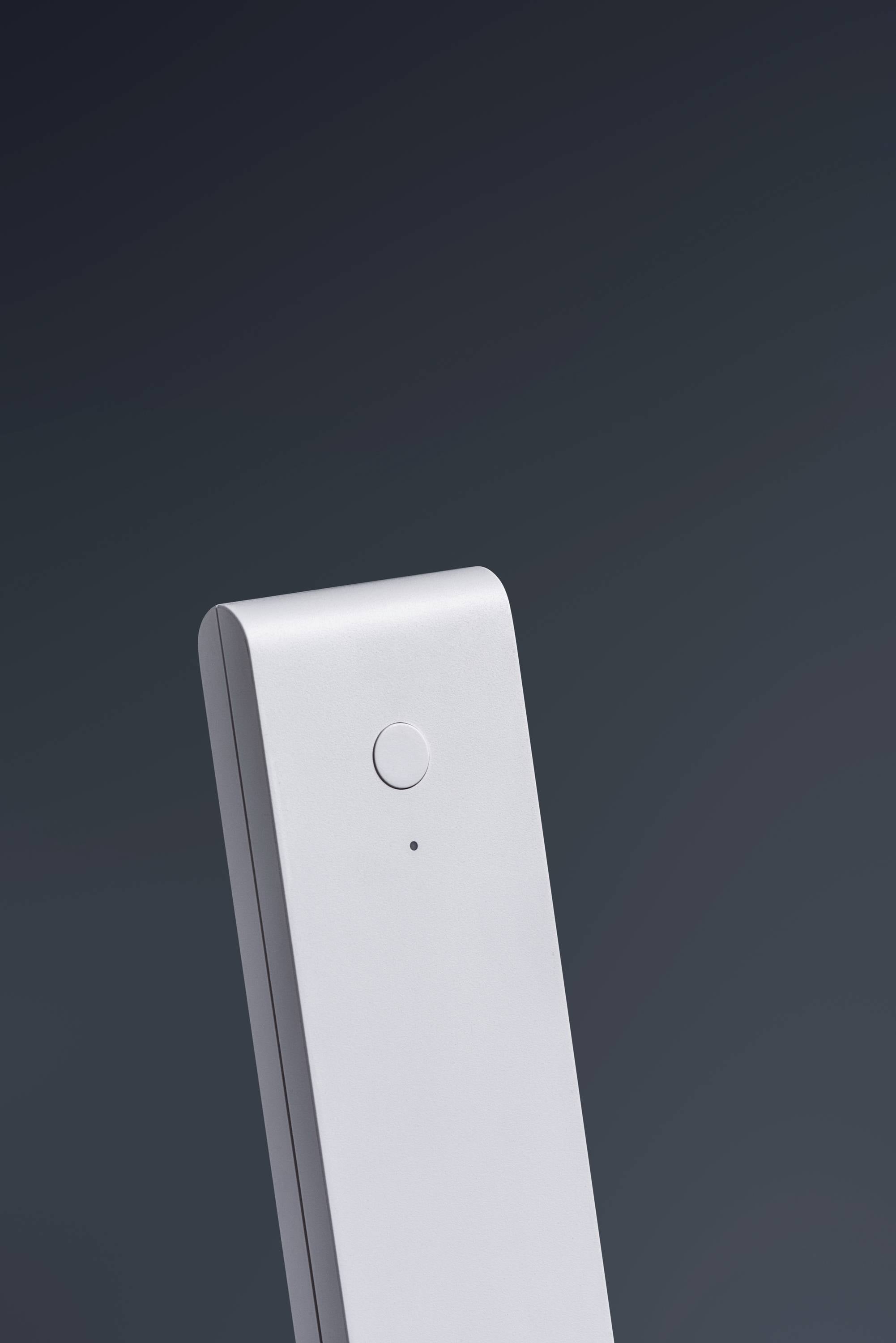 Prosty, nowoczesny sprzęt z jednym przyciskiem i wyświetlaczem LED, umieszczony na ciemnym tle, prawdopodobnie element pilota.