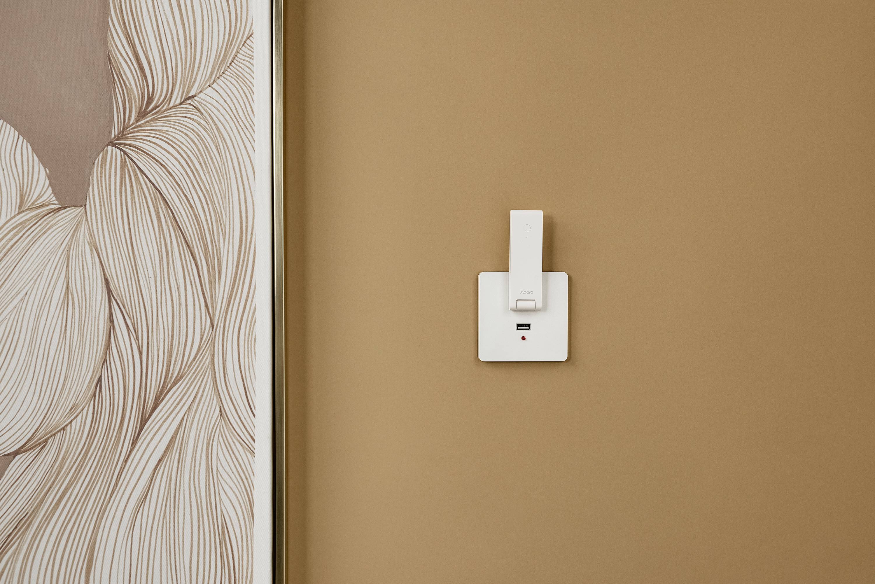 Ściana z nowoczesnym wzorem po lewej stronie i białym włącznikiem światła po prawej stronie na beżowym tle. Minimalistyczny design.