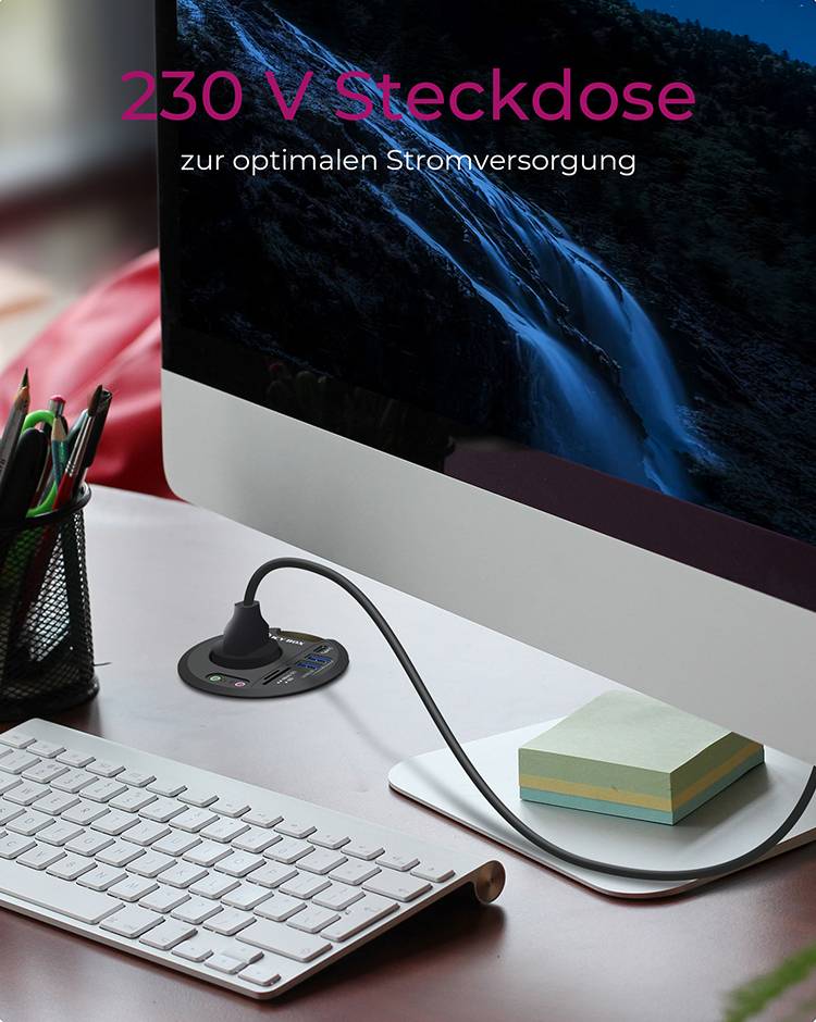 Ekran komputerowy na biurku, podłączony do gniazda elektrycznego 230 V dla optymalnego zasilania. Obok artykuły biurowe.