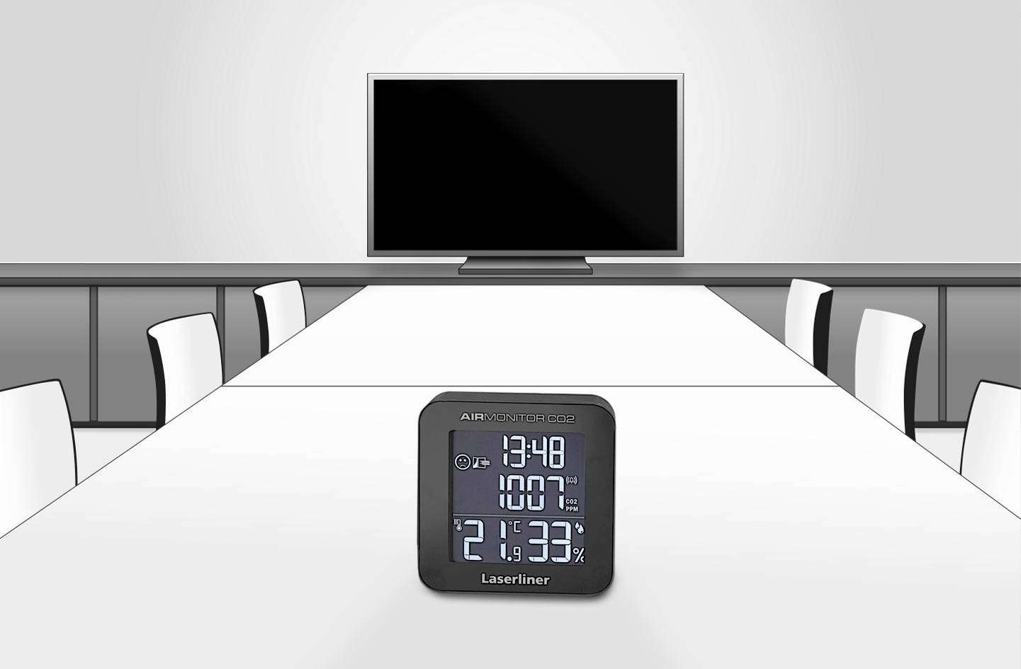 Mały, cyfrowy higrometr wyświetla godzinę, temperaturę i wilgotność powietrza w nowoczesnej sali konferencyjnej z białym stołem i krzesłami.