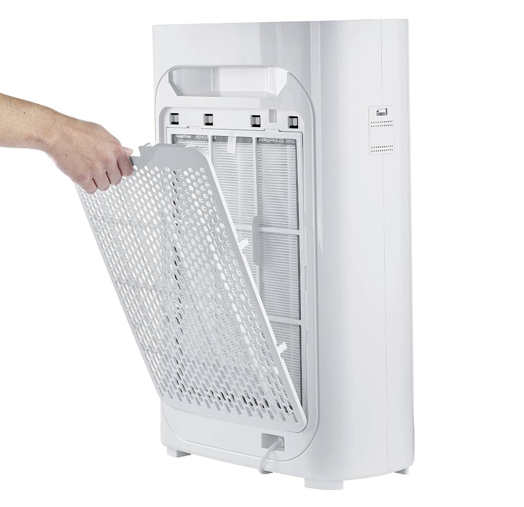 Osoba wyjmuje filtr z białego oczyszczacza powietrza. Filtr jest prostokątny i przypominający siatkę, odpowiedni do konserwacji urządzenia.