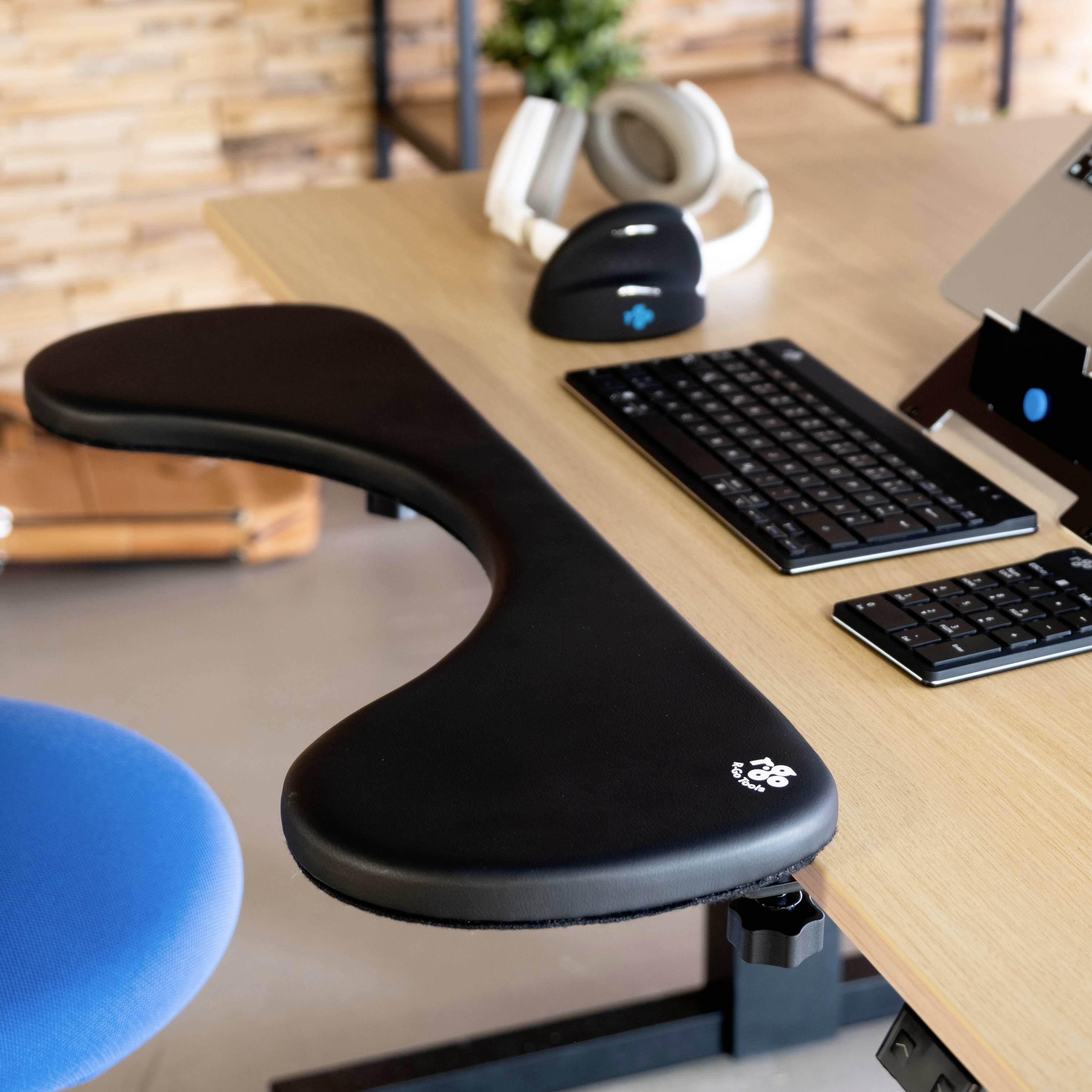 Ergonomiczny sprzęt komputerowy na biurku, składający się z klawiatury, myszy i słuchawek, wspierający wygodną pracę.