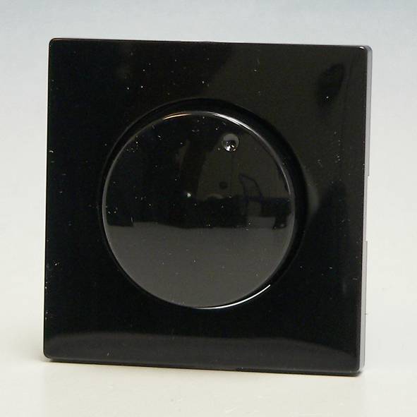 Czarny włącznik światła z okrągłym pokrętłem na jasnym tle.