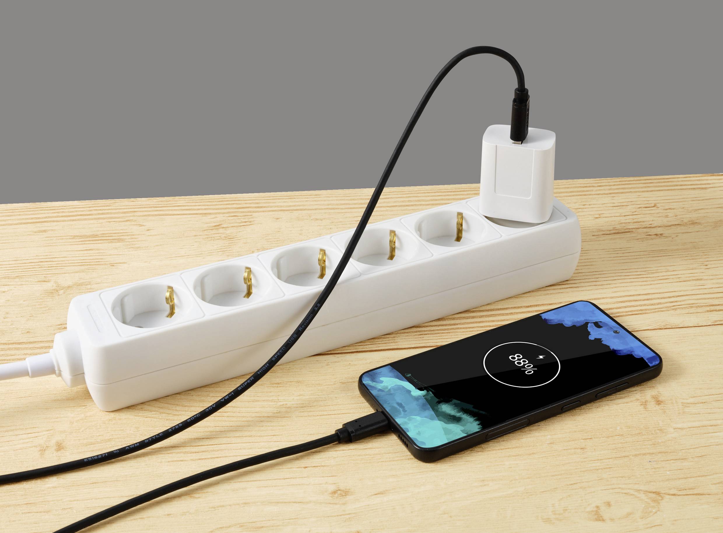 Smartfon jest ładowany kablem podłączonym do listwy zasilającej. Poziom naładowania baterii wskazuje 80%.