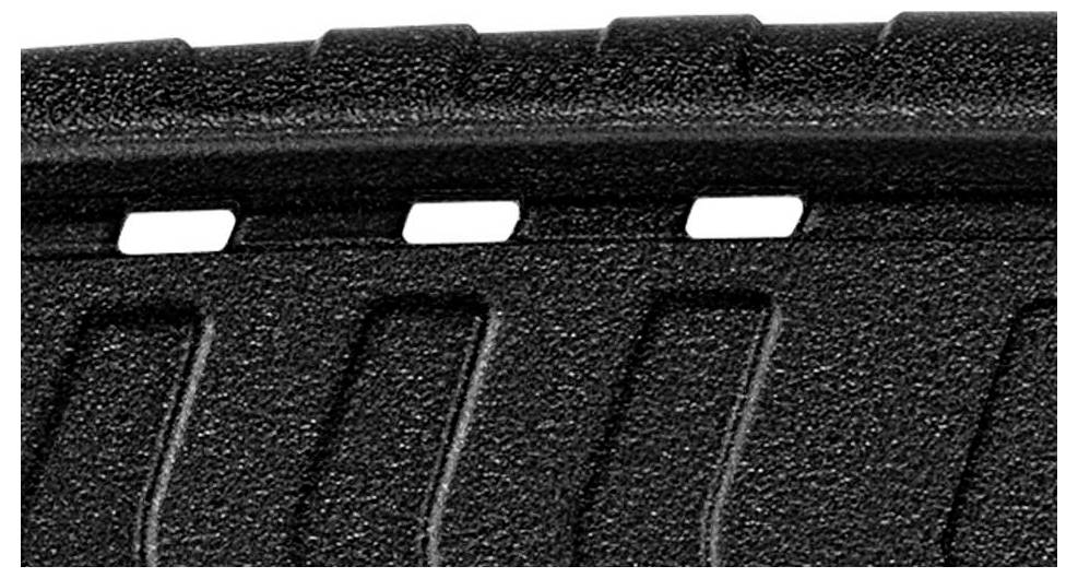 Zbliżenie strukturyzowanego, czarnego materiału z prostokątnymi wycięciami wzdłuż jednej z krawędzi.