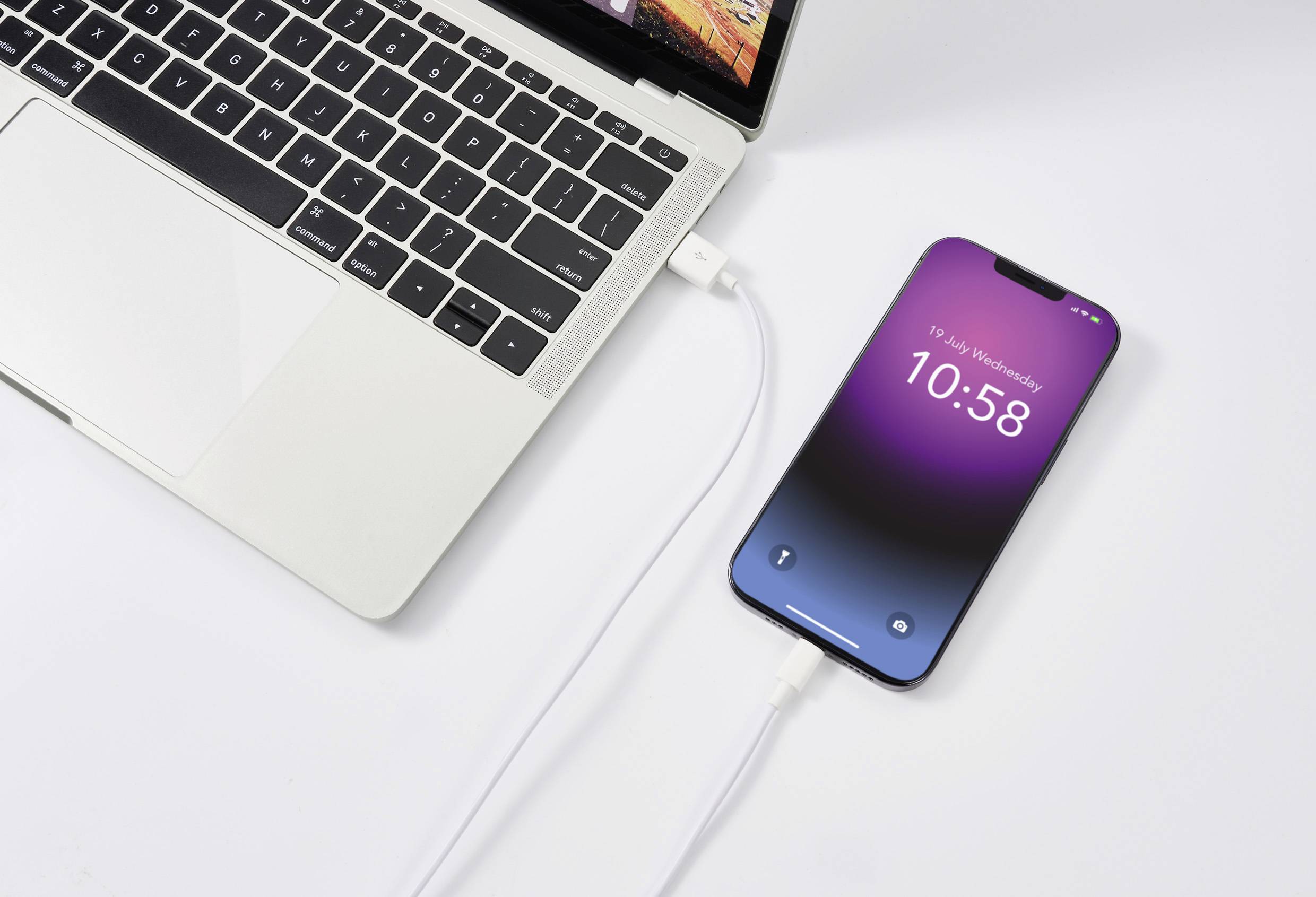 Smartfon jest podłączony do laptopa za pomocą kabla. Na ekranie telefonu wyświetlana jest godzina '10:58'.