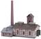 Model historycznej fabryki z wysokim kominem, wieloma budynkami o ceglastych elewacjach i dachach dwuspadowych.