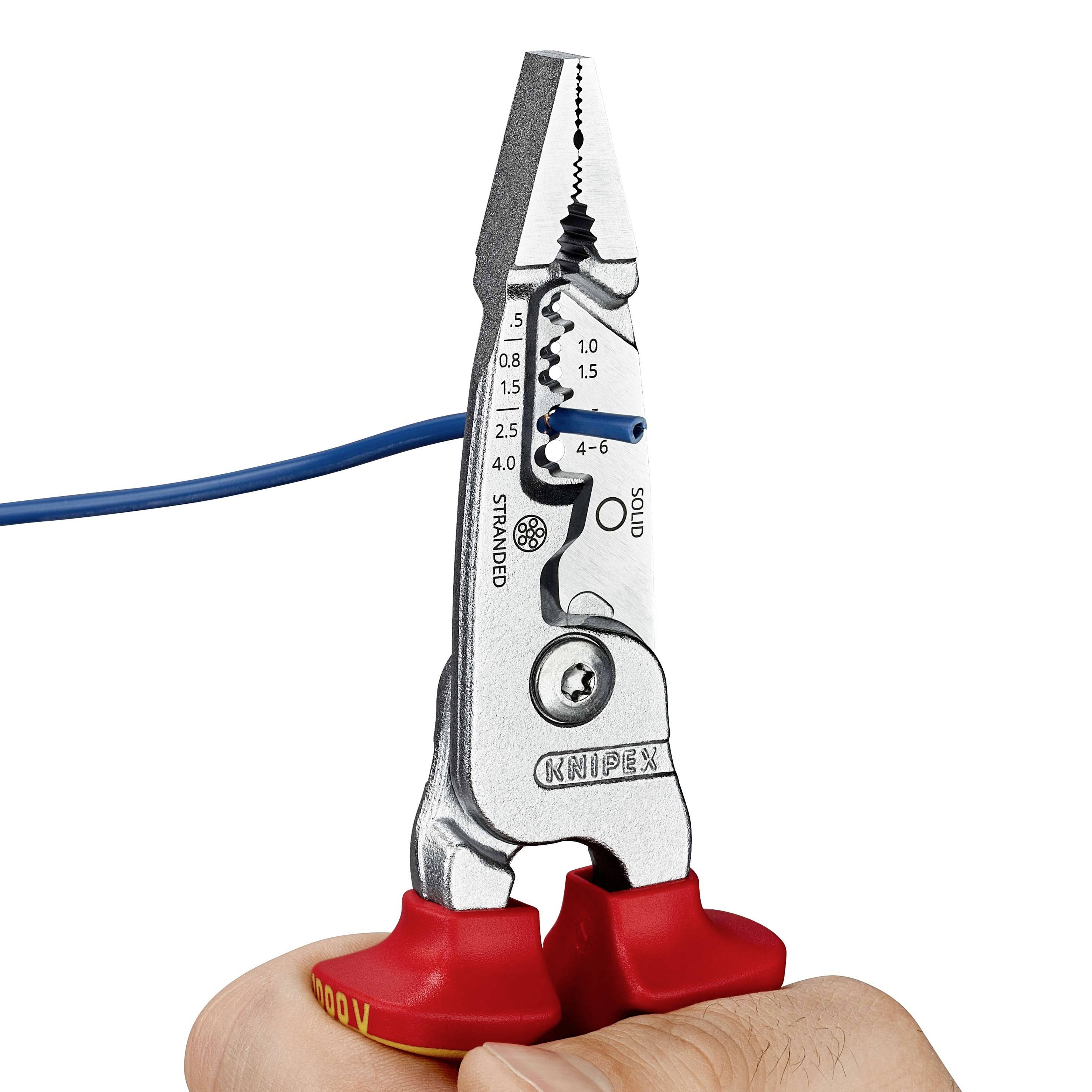 Ręka trzyma szczypce do zdejmowania izolacji z niebieskim przewodem, gotowa do cięcia. Szczypce mają czerwone uchwyty i podziałki pomiarowe.