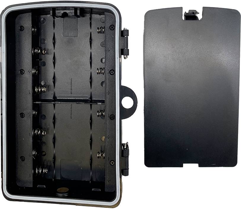 Czarne plastikowe pudełko baterii, otwarte. Po lewej: komora z sprężynkami baterii i miejscem na baterie. Po prawej: pokrywa.