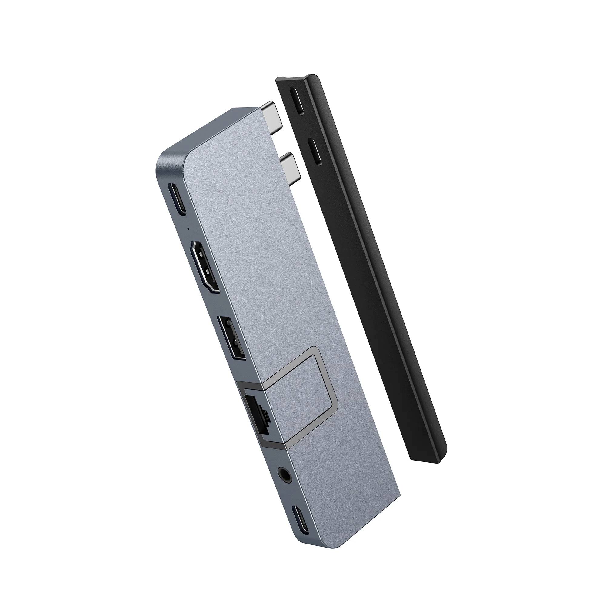 Szary i czarny hub USB z wieloma portami, w tym USB, HDMI i Ethernet, unosi się na białym tle.