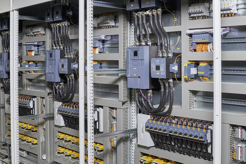 Elektryczny rozdzielnik elektryczny z okablowaniem i urządzeniami łączeniowymi w pomieszczeniu technicznym. Kluczowe komponenty są widocznie zamontowane.