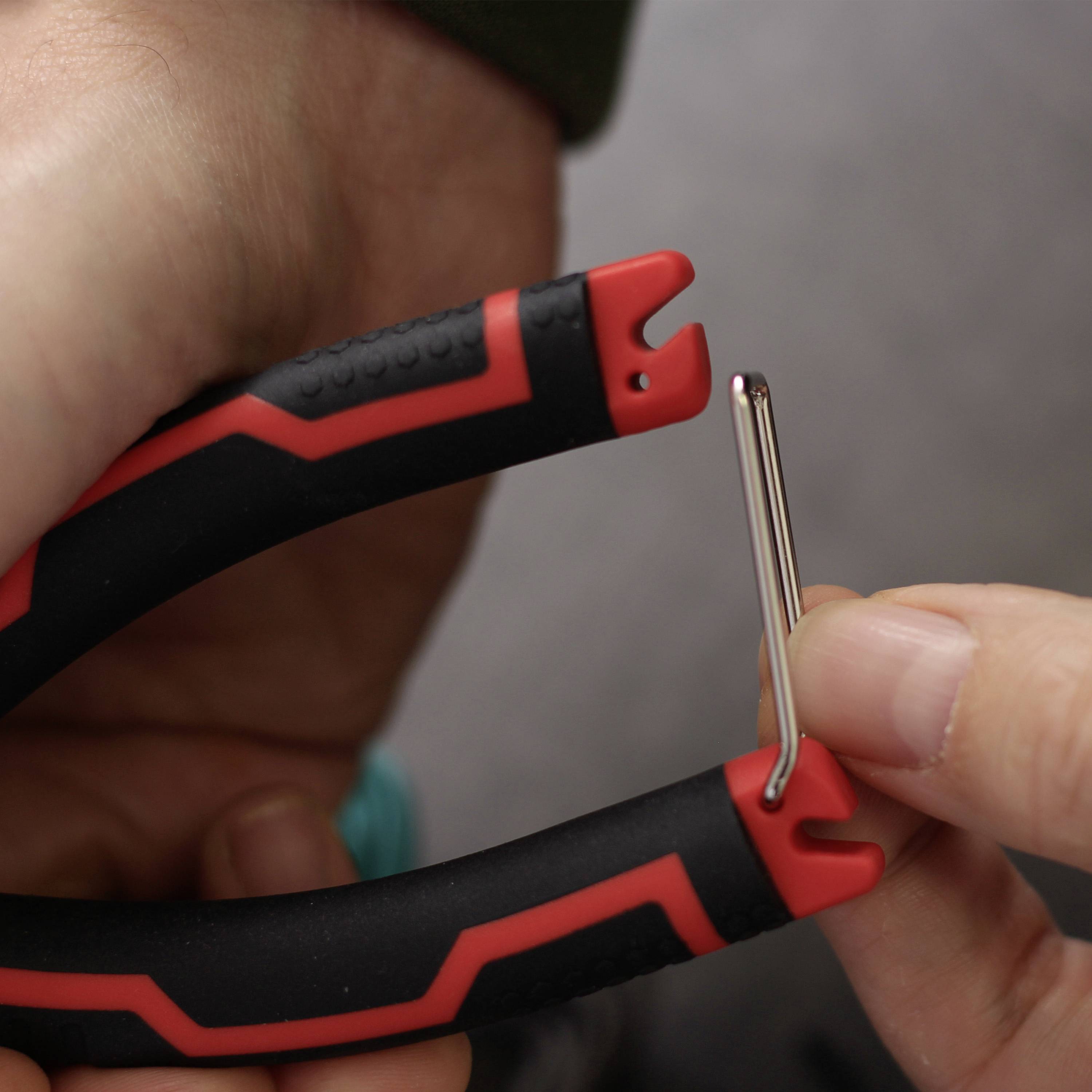 Jedna ręka trzyma pasek z czerwono-czarnym wzorem. Druga ręka wsuwa bolec w otwór paska.