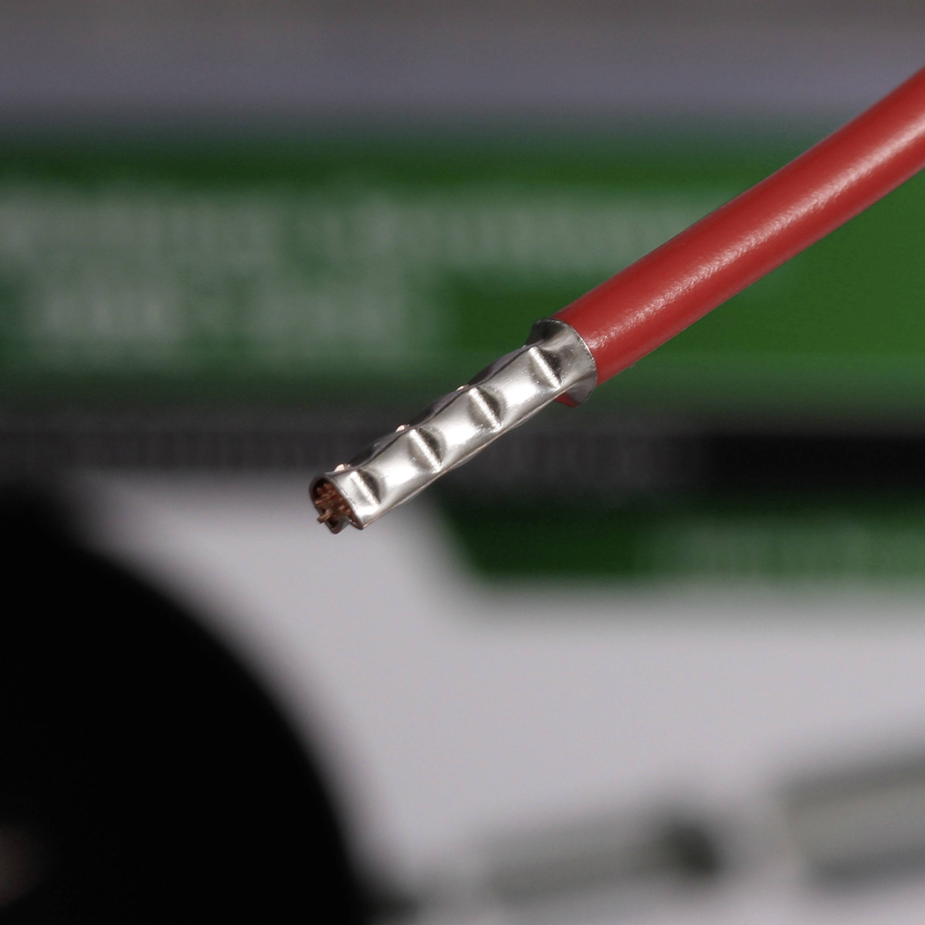 Zbliżenie czerwonego i srebrnego kabla z odsłoniętym miedzianym przewodem na końcu; rozmyte tło.