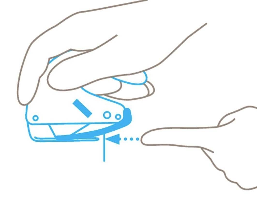 Jedna ręka trzyma zszywacz i naciska go. Palec wskazuje miejsce zszycia.
