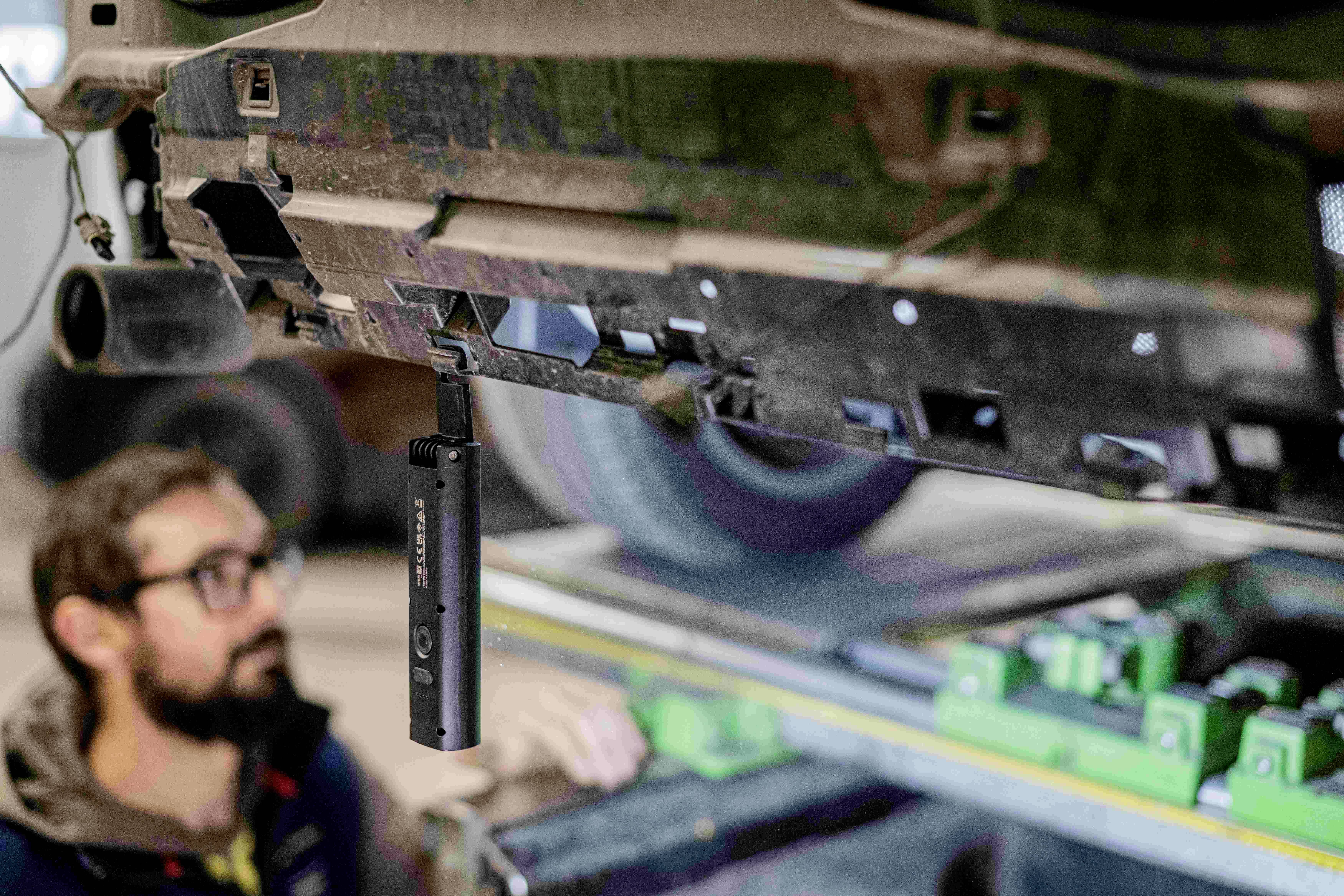 Mechanik sprawdza podwozie pojazdu w warunkach warsztatowych, używając narzędzia.