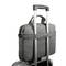 Szara, melanżowa teczka na walizce z kółkami. Torba posiada dwa uchwyty oraz pasek do mocowania na uchwycie walizki.