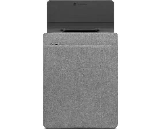 Zamknięty laptop w szarym pokrowcu materiałowym, ustawiony na stole. Obok niego leży długopis.