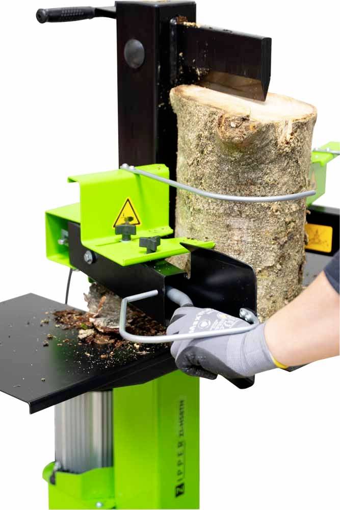 Łuparka w akcji: Dłoń w rękawicach obsługuje maszynę, podczas gdy gruby pień drewna jest rozłupywany. Widoczne są urządzenia zabezpieczające.