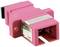 Różowy adapter światłowodowy o prostokątnym kształcie z metalowymi złączami, odpowiedni do połączeń kabli światłowodowych.