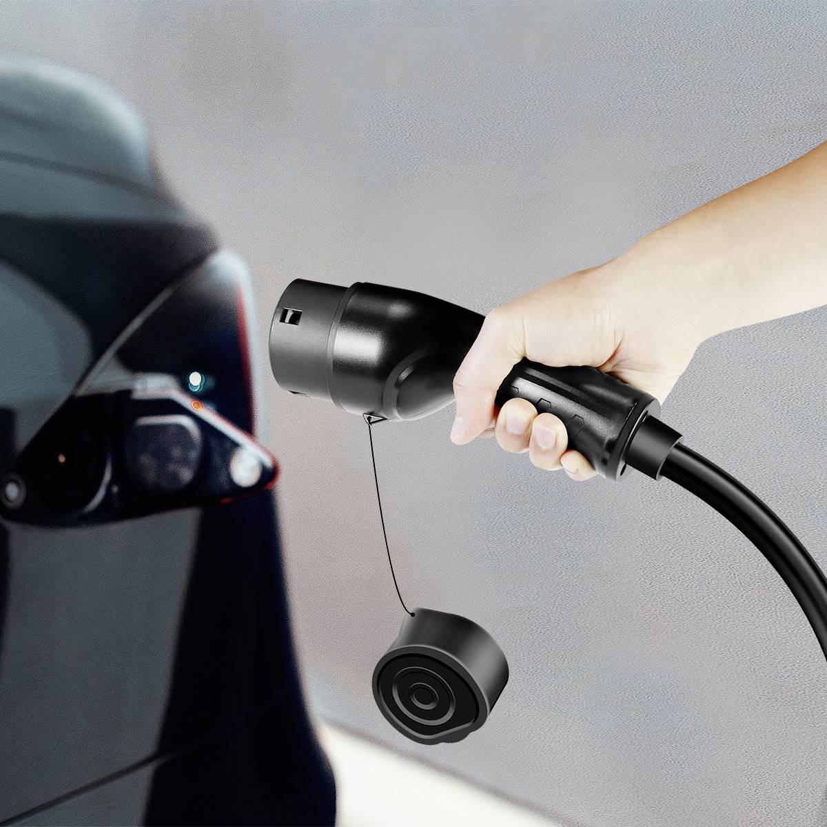 Dłoń trzyma przewód ładujący przed złączem ładowania samochodu elektrycznego.