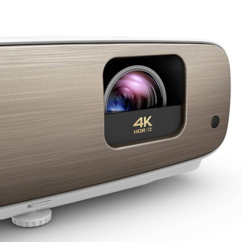 Zbliżenie nowoczesnego projektora 4K-HDR z elegancką metalową obudową z przodu i widocznym obiektywem.