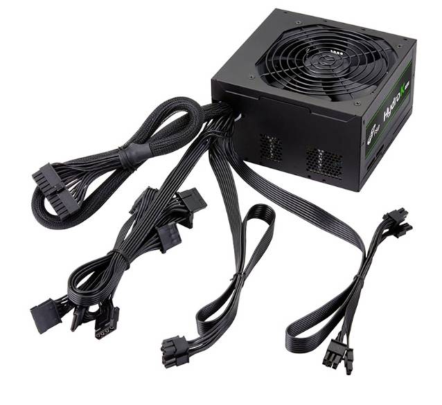 Czarny zasilacz komputerowy z wieloma wiązkami kabli i złączami jest przedstawiony na białej powierzchni.