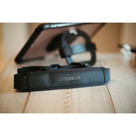 Etui na tablet z uchwytem leżące na drewnianym stole. Etui posiada logo 'Otterbox' i zapewnia stabilność oraz ochronę.