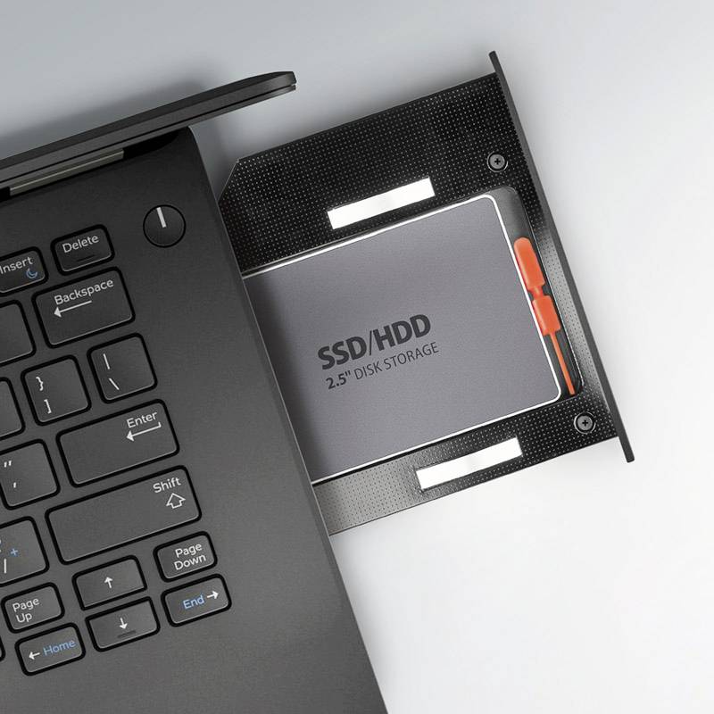 Klawiatura laptopa po lewej stronie, po prawej adapter SSD/HDD z włożonym dyskiem twardym. Podstawa montażowa dla nośników danych o rozmiarze 2,5 cala.