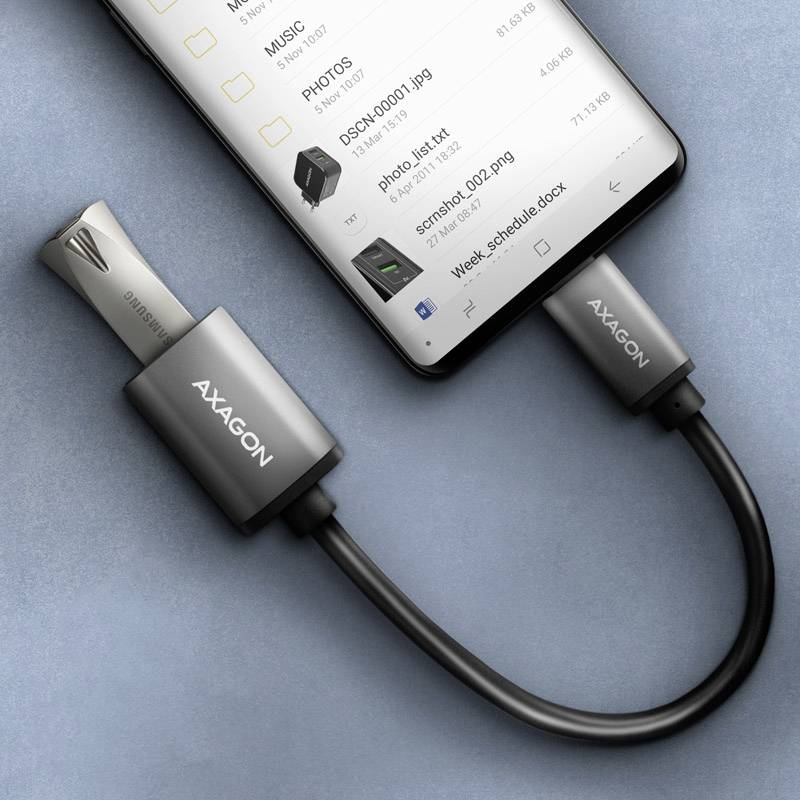 Smartfon podłączony kablem USB OTG do pendriva. Ekran wyświetla pliki i foldery.