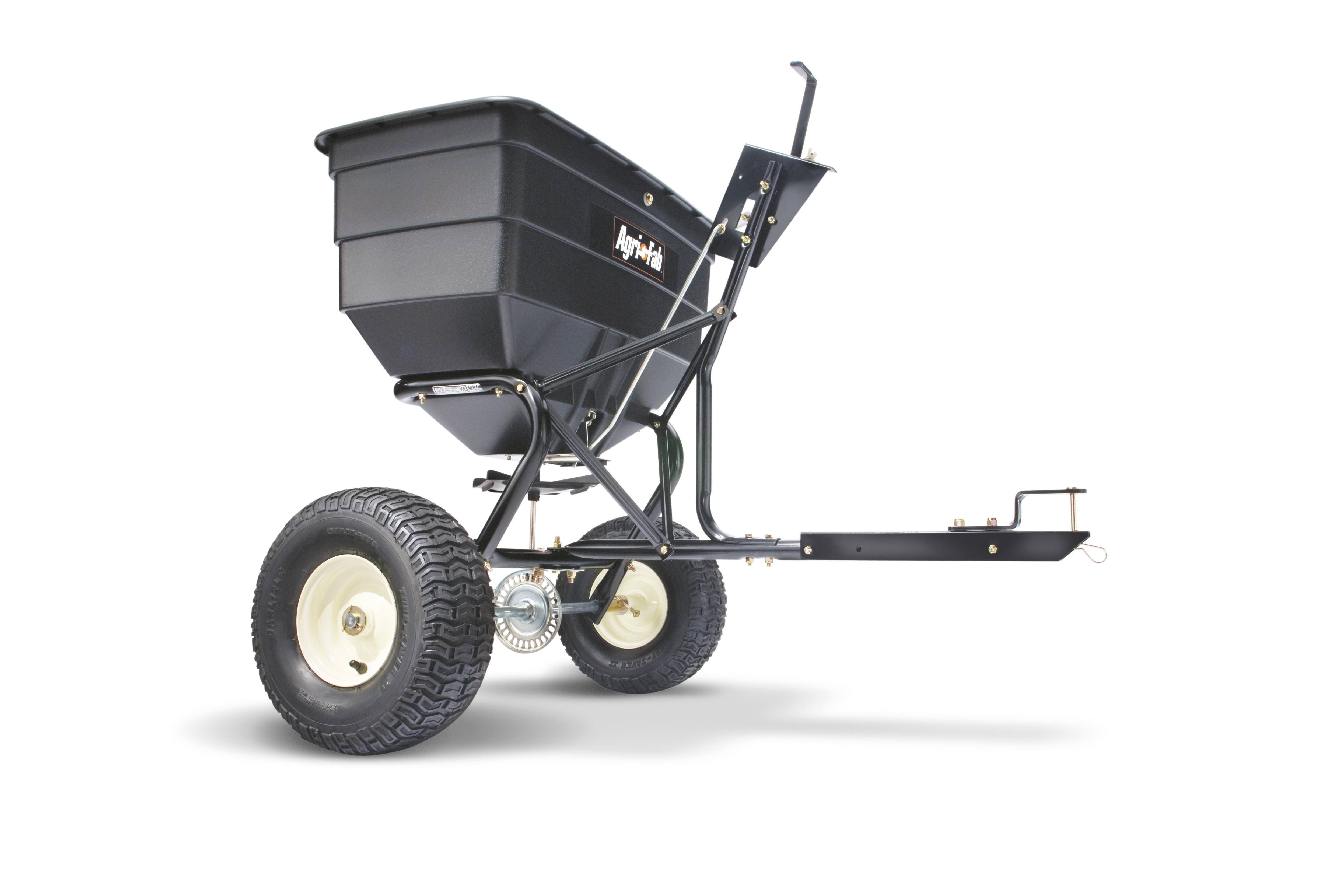 Rozsiewacz nasion z dwoma dużymi kołami, czarnym zbiornikiem i metalową ramą; do łatwego wysiewu nasion lub rozsypywania nawozów.
