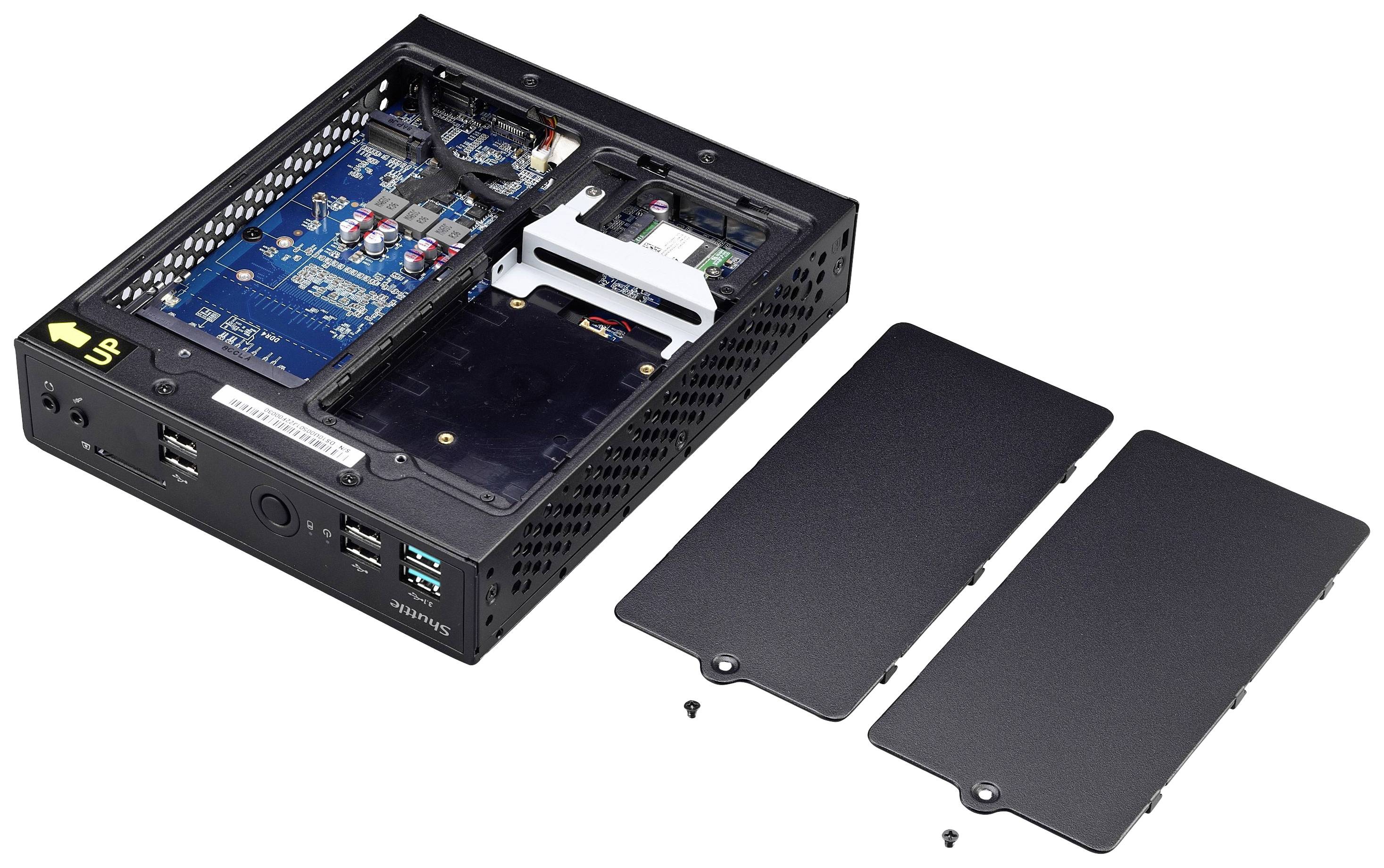 Otwarty mini-komputer prezentuje płytę główną i komponenty wewnętrzne. Obok leżą dwie pokrywy i śruby.