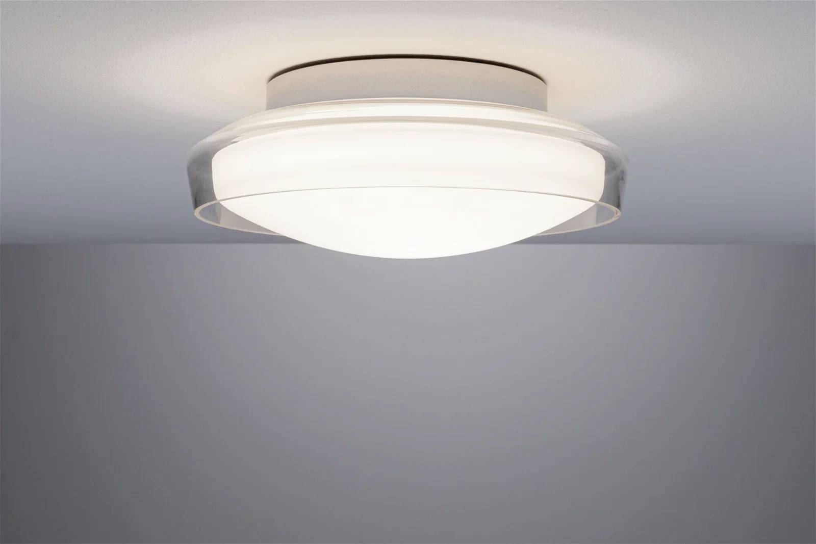 Lampa sufitowa z okrągłym szklanym kloszem emituje ciepłe światło i zapewnia równomierne oświetlenie pomieszczenia.