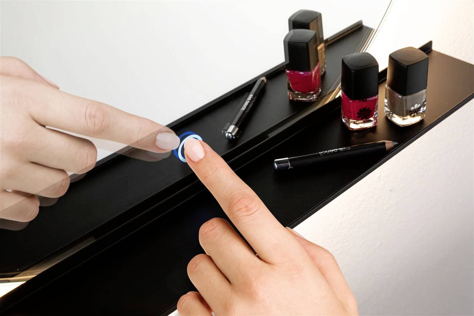 Palec naciska przycisk podświetlonego lustra kosmetycznego, aby włączyć lub wyłączyć światło. Obok znajduje się flakonik z lakierem do paznokci.