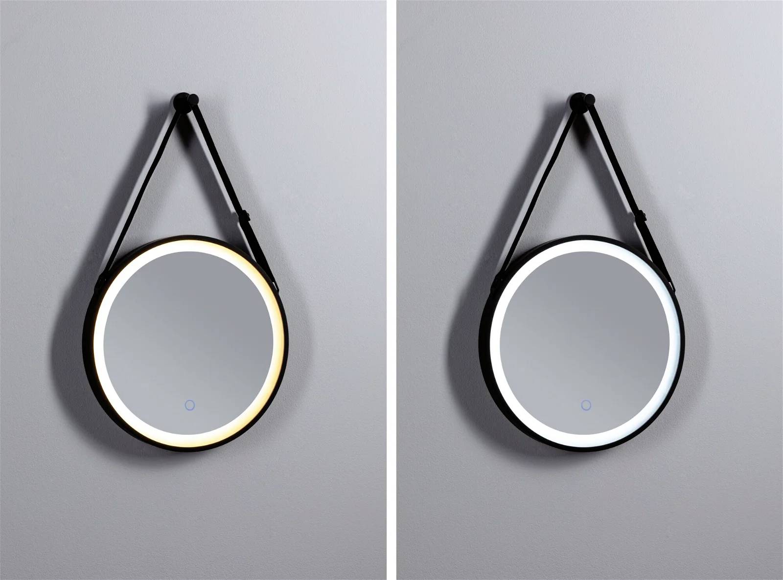Dwa okrągłe lustra ścienne umieszczone obok siebie, jedno z ciepłą, a drugie z zimną ramką świetlną LED. Oba zawieszone na czarnych pasach.