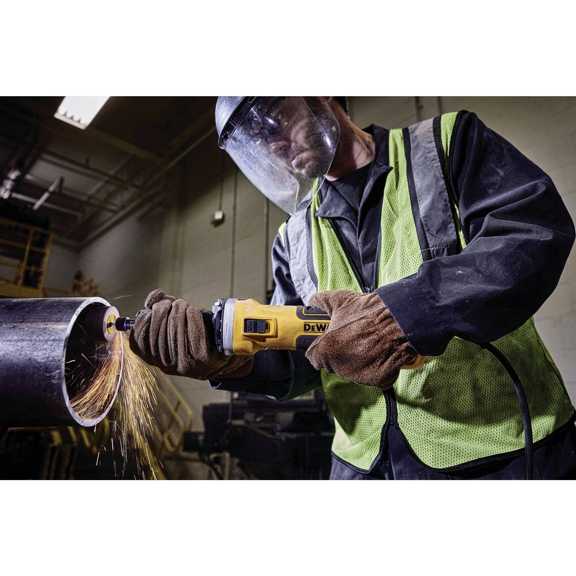 Osoba w odzieży ochronnej przycina metal kątówką. Od miejsca cięcia odlatują iskry.