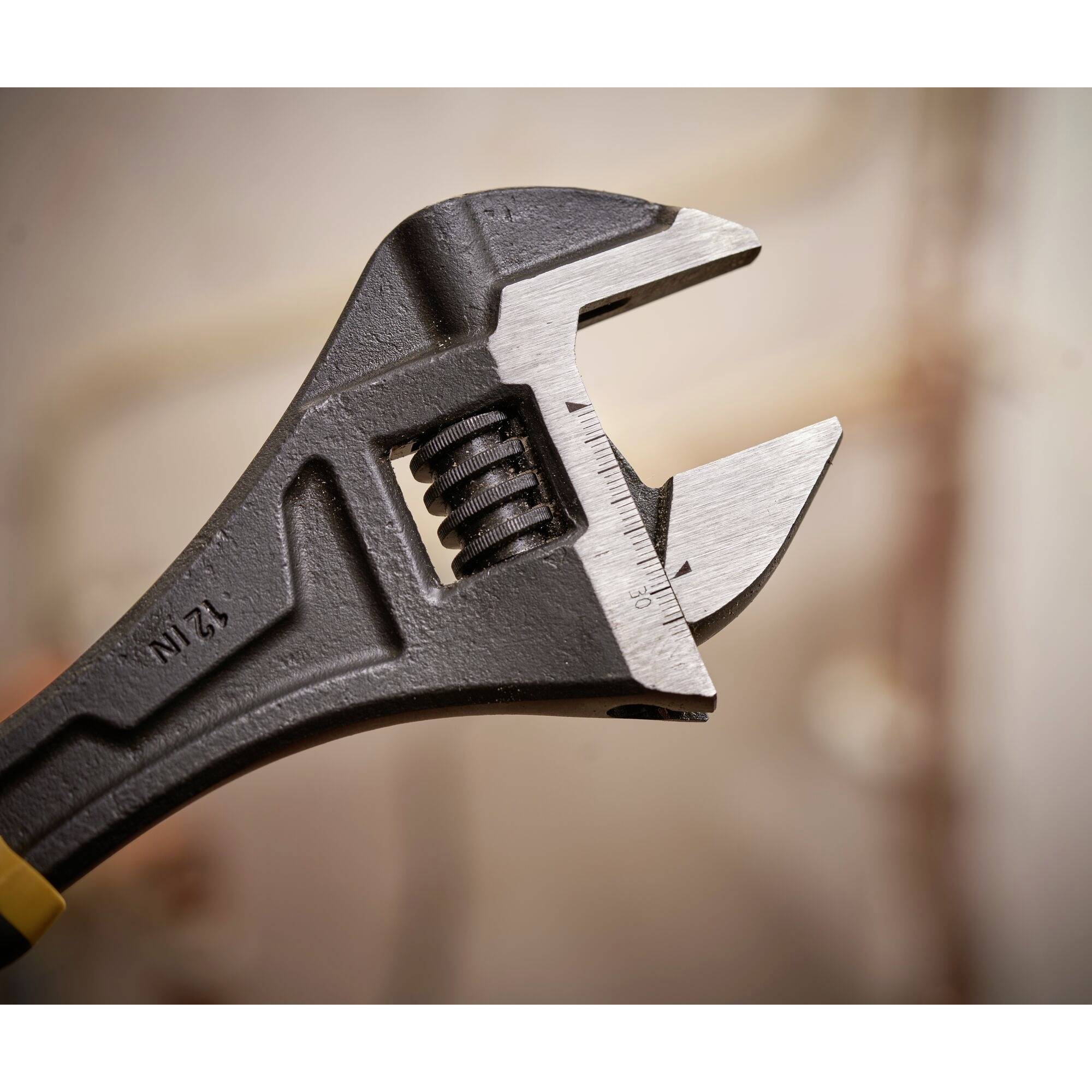 Regulowane szczypce w zbliżeniu, obracane, aby chwycić nakrętkę. Tło rozmyte i neutralne.