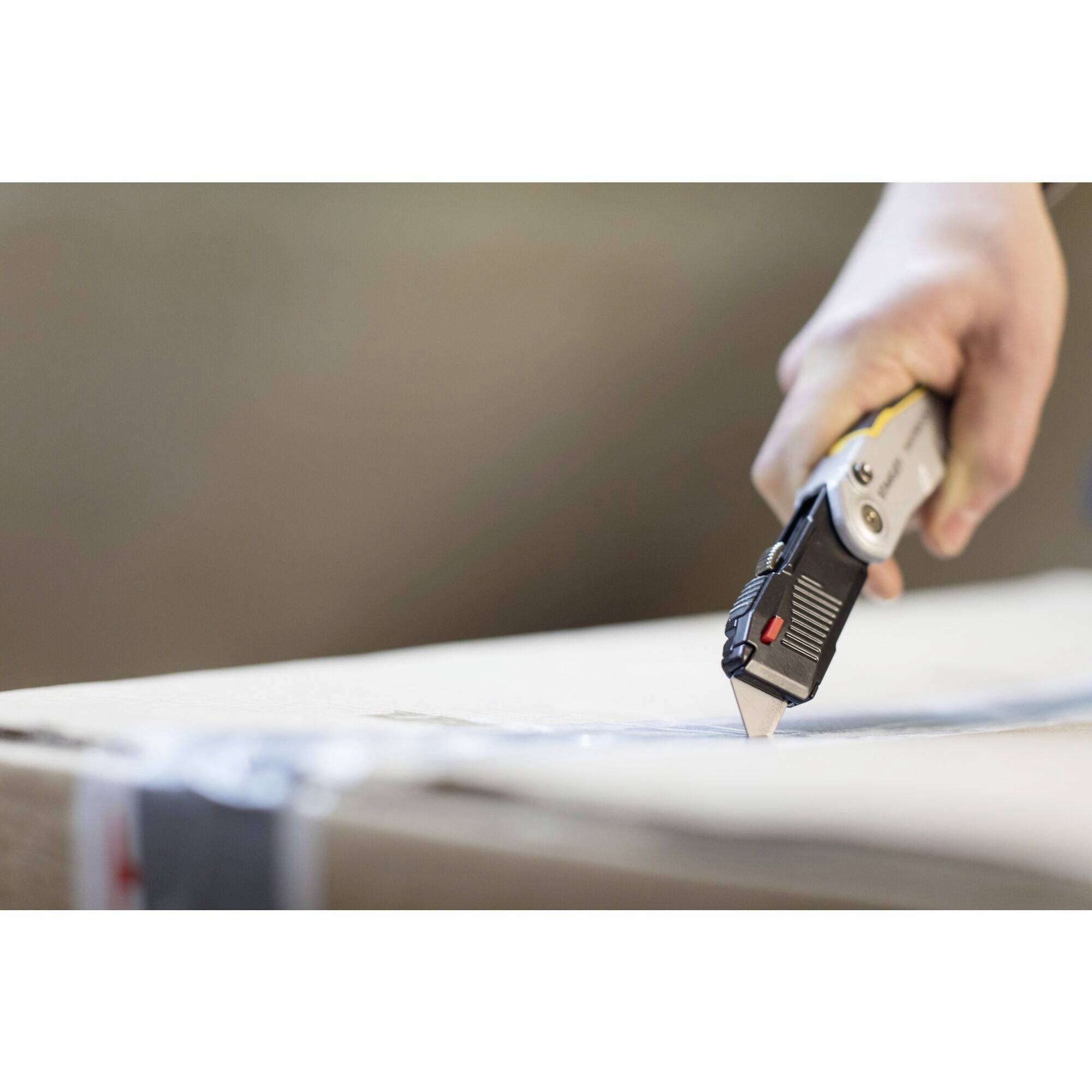 Ręka przecina karton nożem do tapet.