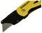 Żółty i czarny nóż do dywanów z widocznym ostrzem i napisem firmowym.