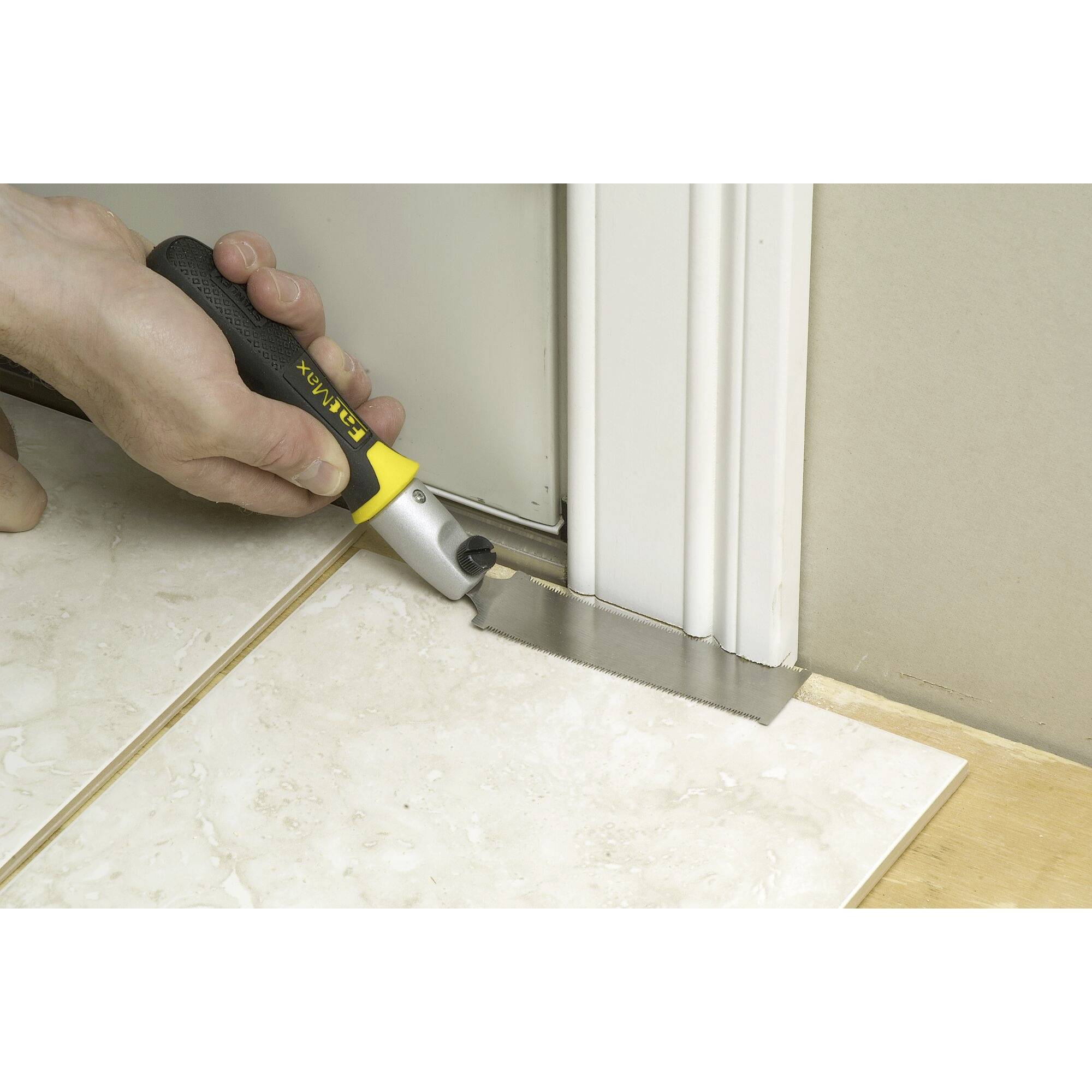 Ręka używa narzędzia ręcznego Stanley do skrócenia dolnej części ościeżnicy drzwiowej, aby dopasować ją do podłogi.