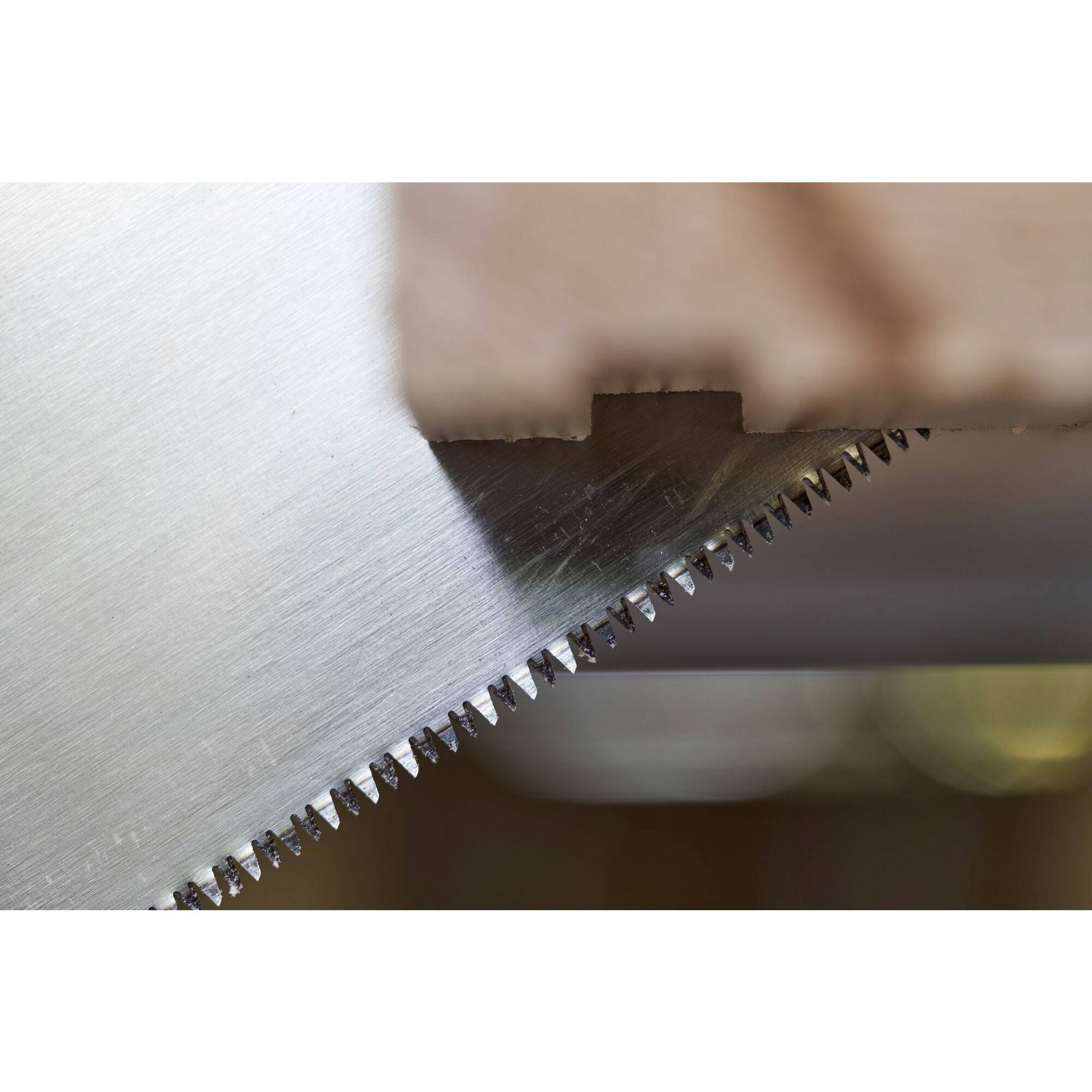 Zbliżenie piły tnącej drewno. Zęby piły są wyraźnie widoczne, co podkreśla jej ostrość i precyzję.