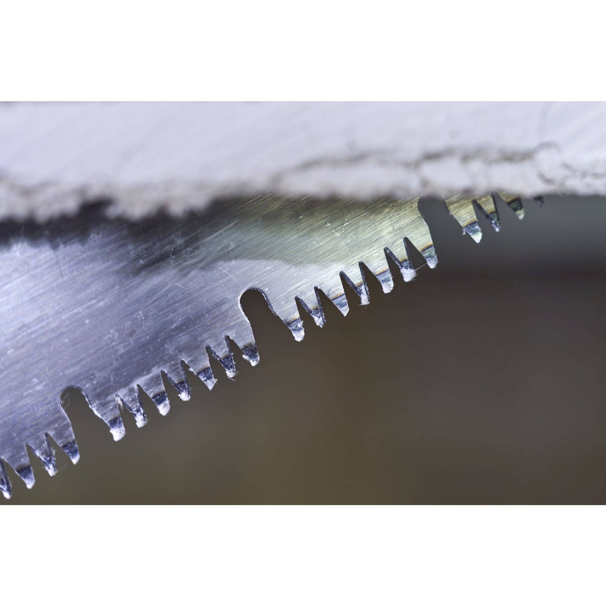 Zbliżenie krawędzi piły z ostrymi zębami, które przecinają kawałek drewna.