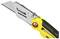 Żółty nóż uniwersalny z wysuniętym ostrzem. Narzędzie posiada czarny uchwyt i srebrną jednostkę tnącą.