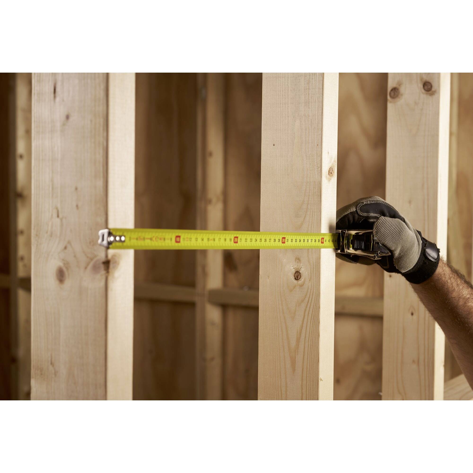 Osoba używa miarki do zmierzenia struktury drewnianej.