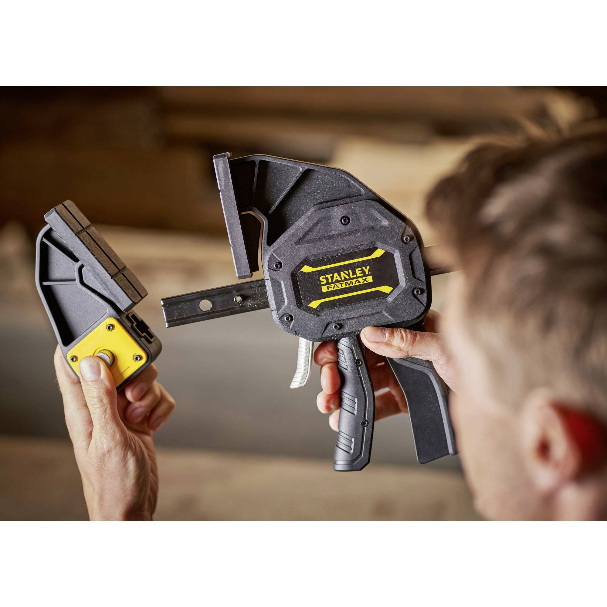Jedna osoba trzyma narzędzie Stanley do prac drewnianych, które jest czarno-żółte. Wydaje się, że sprawdza lub reguluje to narzędzie.