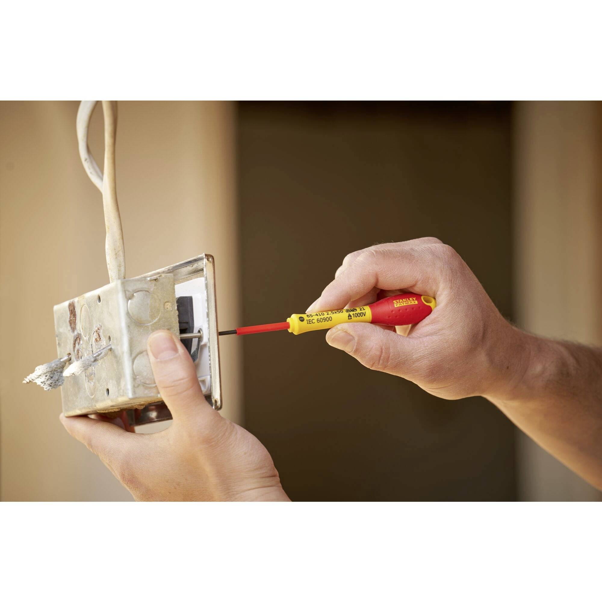 Osoba instaluje włącznik światła za pomocą śrubokrętu. Przełącznik jest częściowo wmontowany w ścianę.