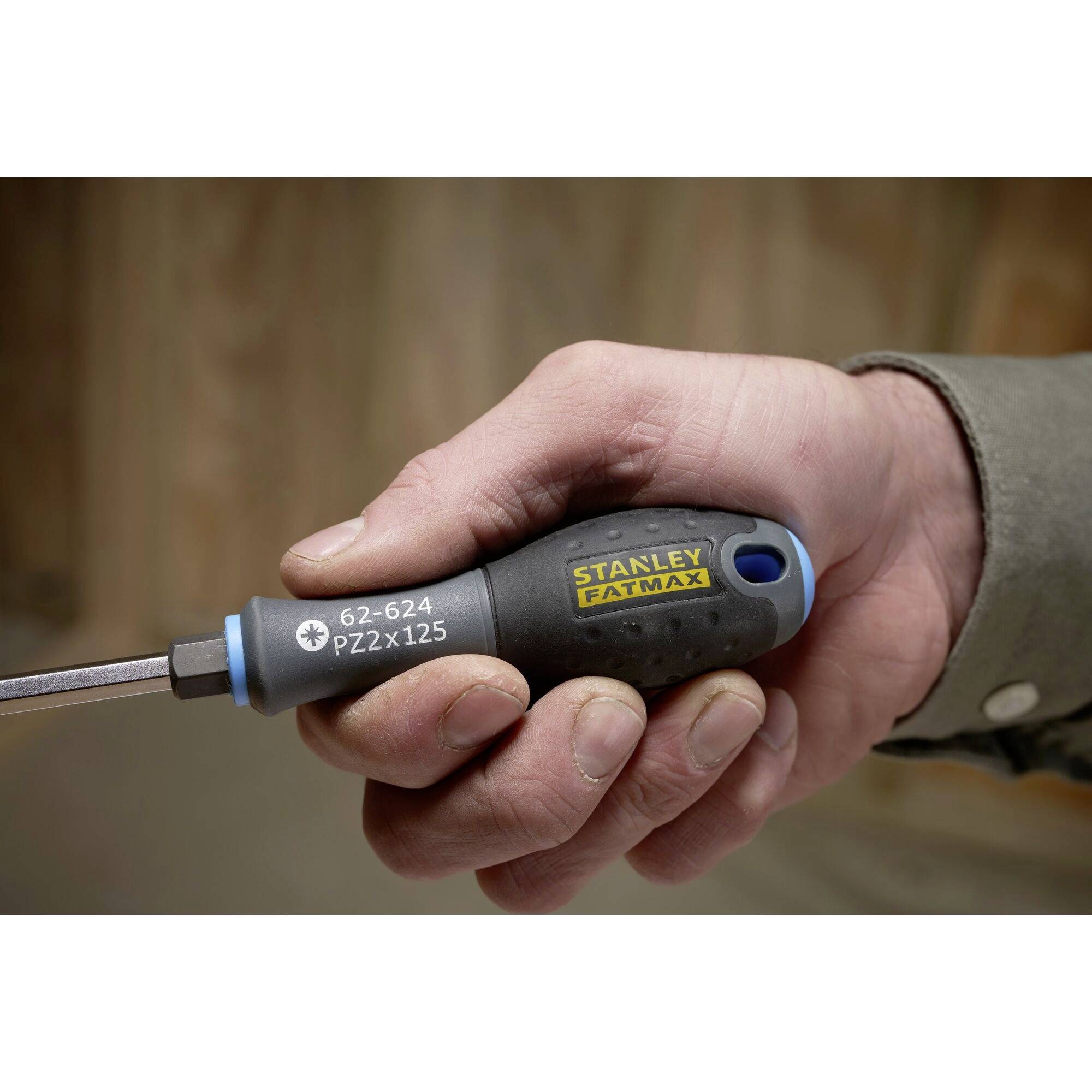 Jedna ręka trzyma wkrętak marki Stanley FatMax, model PZ2x125. Uchwytu jest czarny z niebieskimi akcentami.